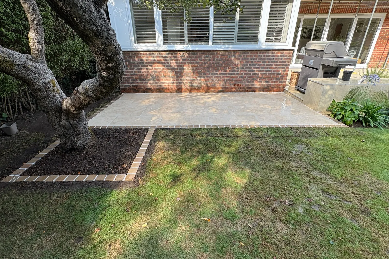 The finished patio from the side, a brick edge round the bed, Send, 2026