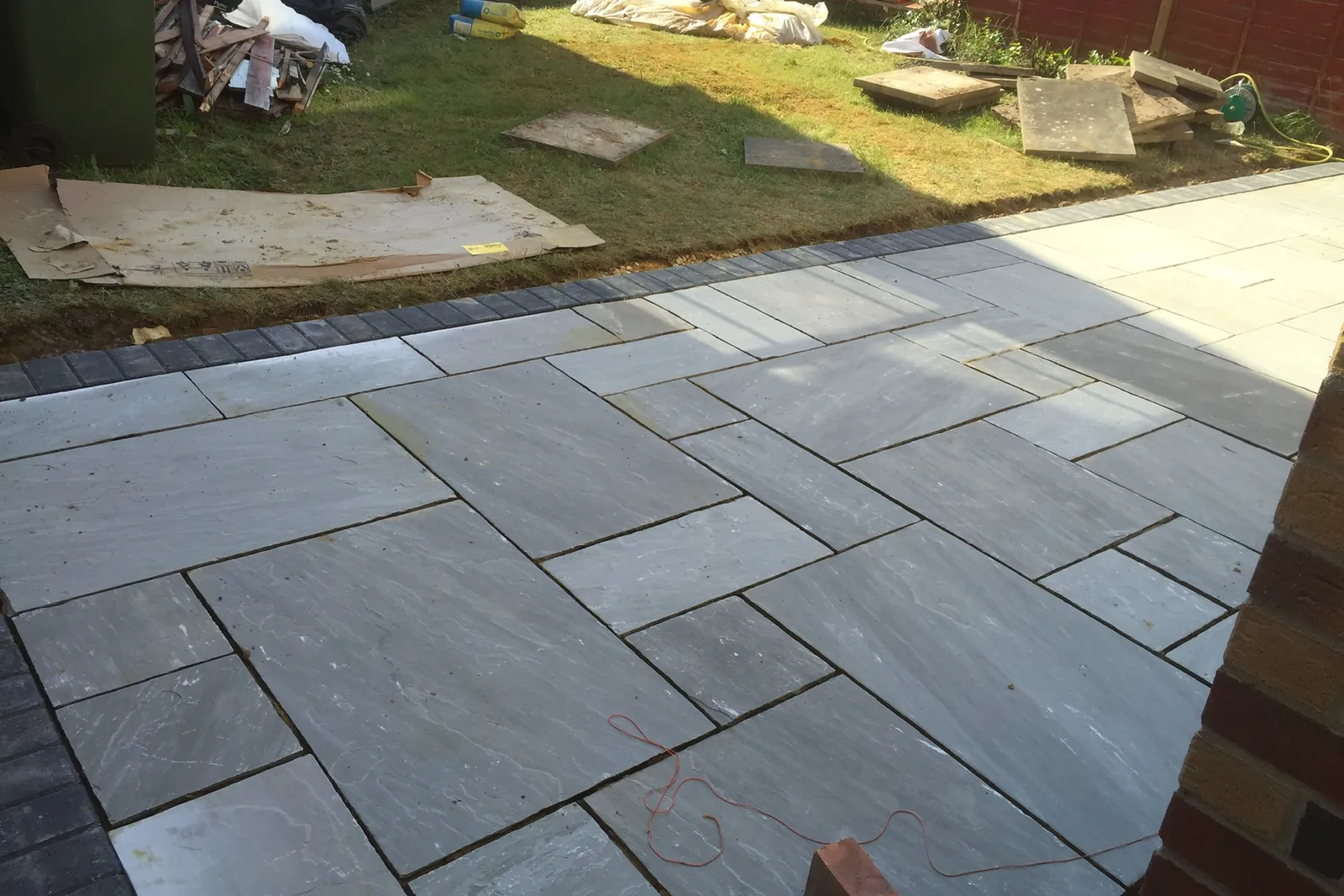 Grey sandstone patio with a charcoal block edge, Slough, 2019