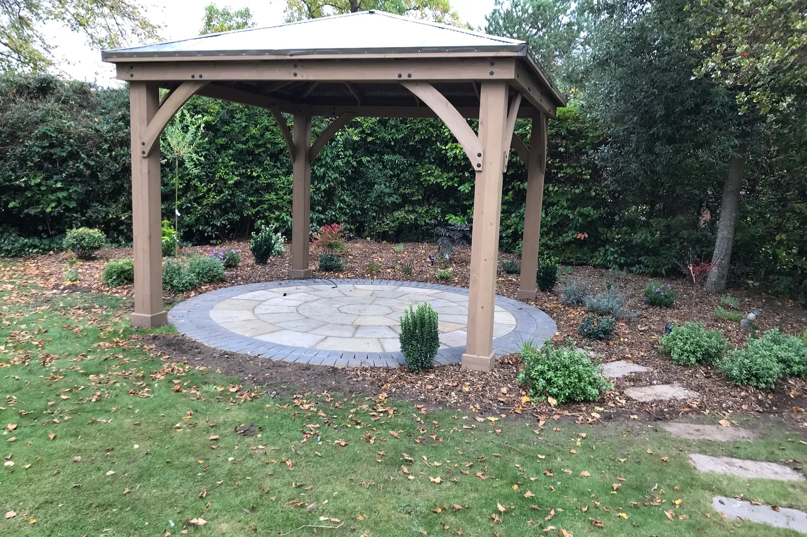 Roofed timber pergola on a circular sandstone patio, finished with planting, Farnham Royal, Slough, 2021